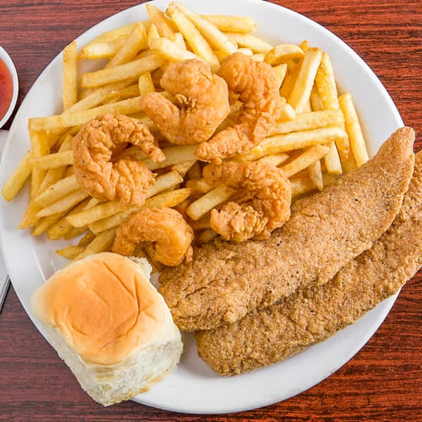 A white plate with fried shrimp, fish fillets, french fries, and a dinner roll.